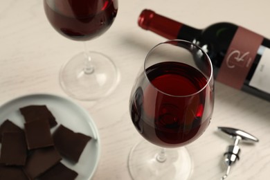 Tasty red wine and chocolate on white wooden table