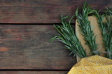 Photo of Bunches of fresh rosemary on wooden table, top view with space for text. Aromatic herb