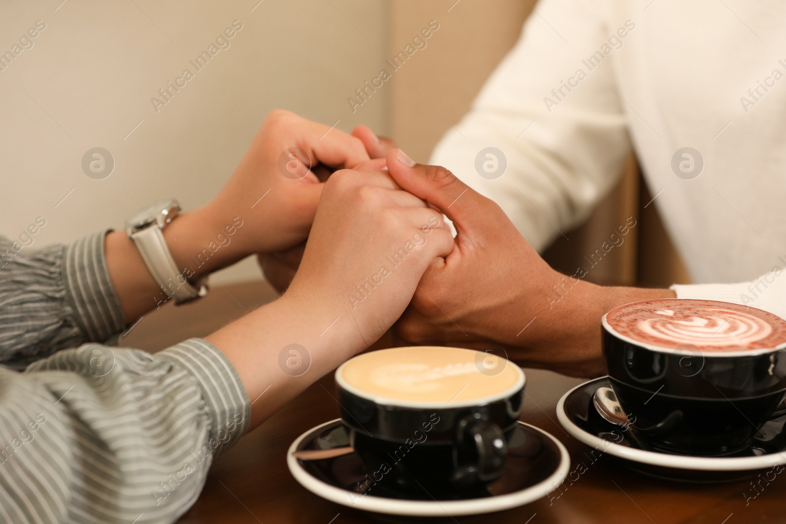 Photo of Romantic date. Couple holding hands together in cafe, closeup