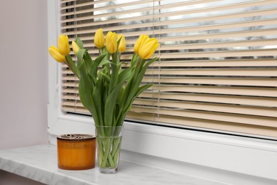Photo of Wonderful tulips and candle on window sill indoors, space for text. Spring atmosphere