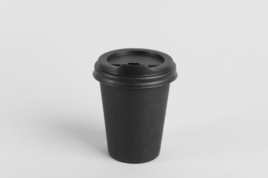 Photo of Black paper cup with plastic lid on light background. Coffee to go