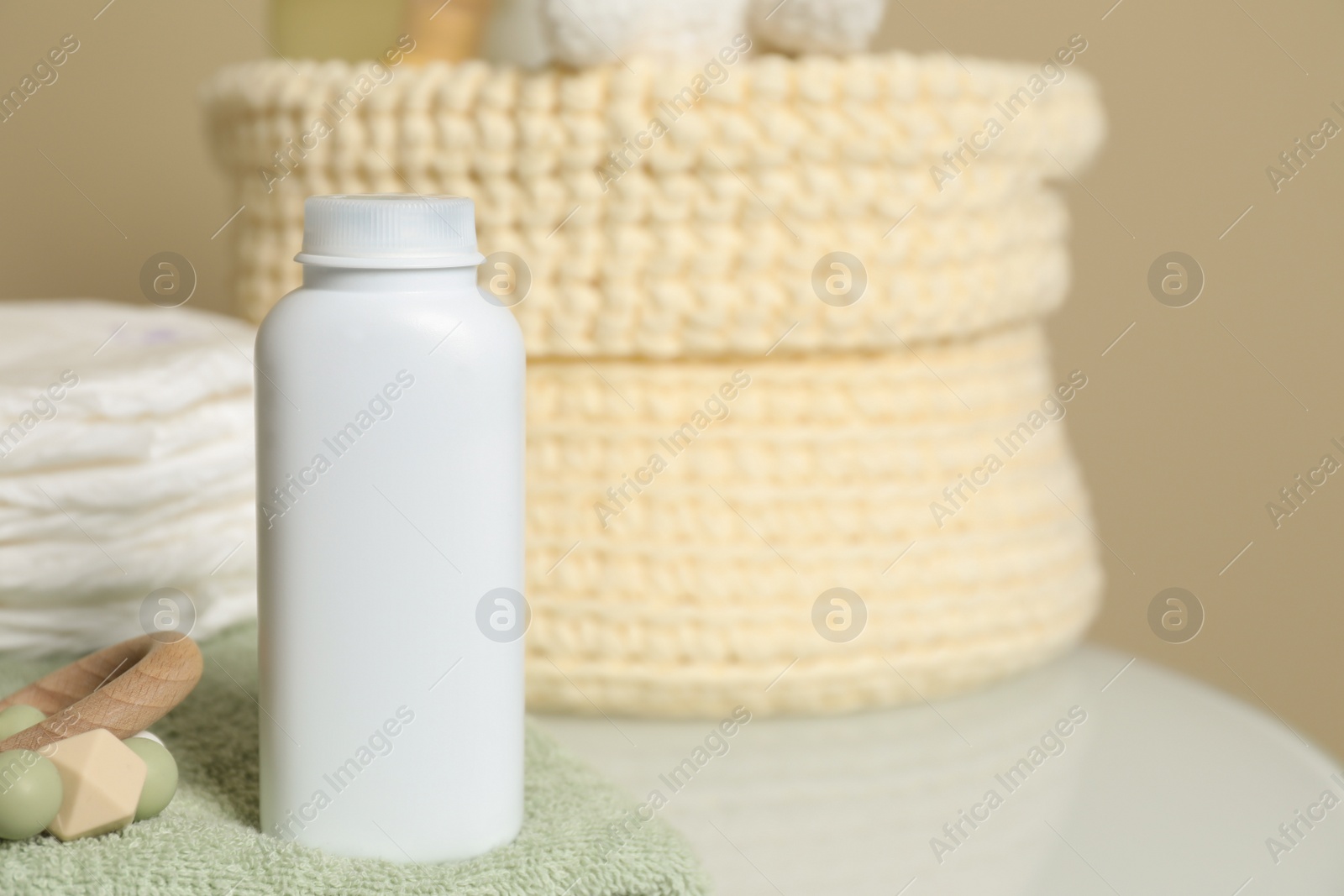 Photo of Bottle of dusting powder, wooden toy, soft towel and diapers on table, space for text. Baby cosmetic product