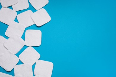 Photo of Many cotton pads on light blue background, flat lay. Space for text