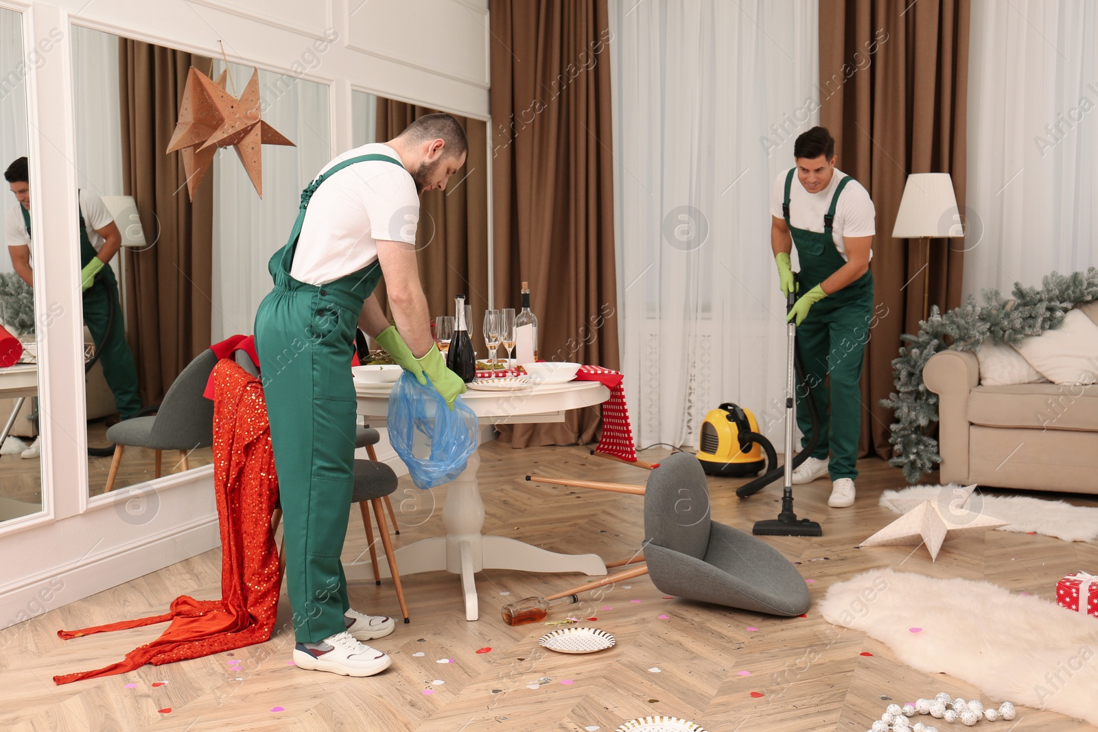 Photo of Cleaning service team working in messy room after New Year party