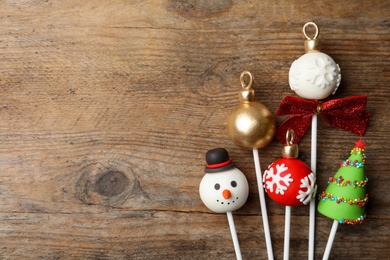 Photo of Delicious Christmas themed cake pops on wooden table, flat lay. Space for text