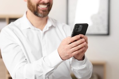 Photo of Smiling man using smartphone in office, closeup