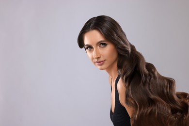 Image of Hair styling. Attractive woman with wavy long hair on grey background, space for text