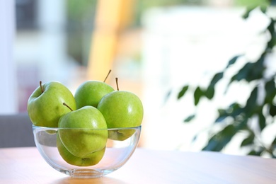 Photo of Bowl of fresh green apples on table indoors. Space for text