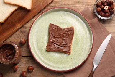 Photo of Toast with tasty nut butter and hazelnuts on wooden table, flat lay