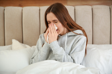 Photo of Sick young woman in bed at home. Influenza virus