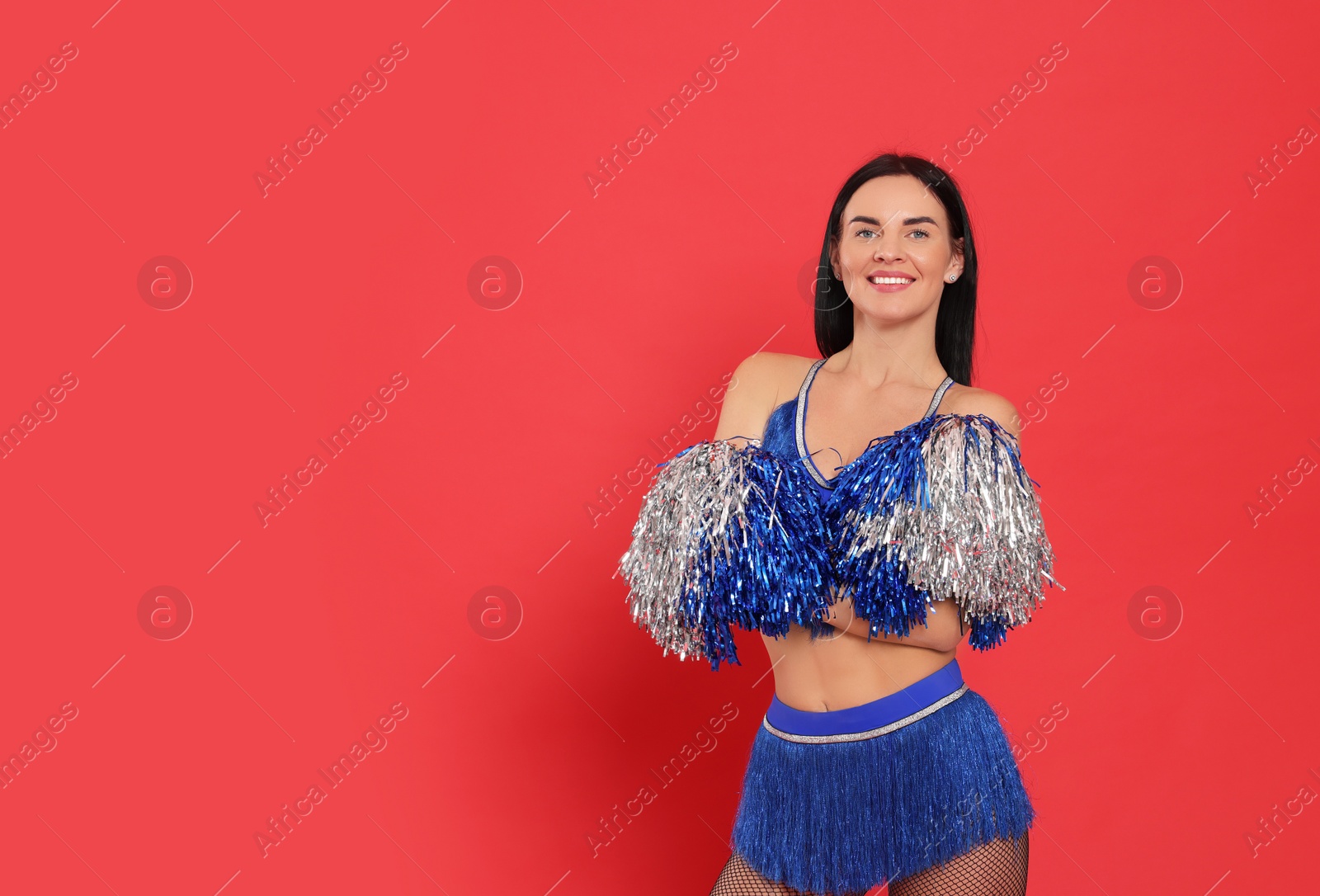 Photo of Beautiful cheerleader in costume holding pom poms on red background. Space for text