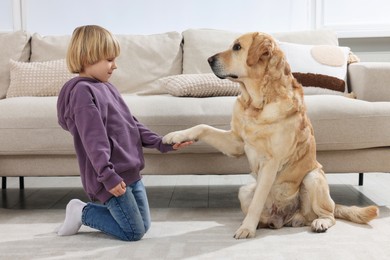 Photo of Cute little child with Golden Retriever on floor at home. Adorable pet