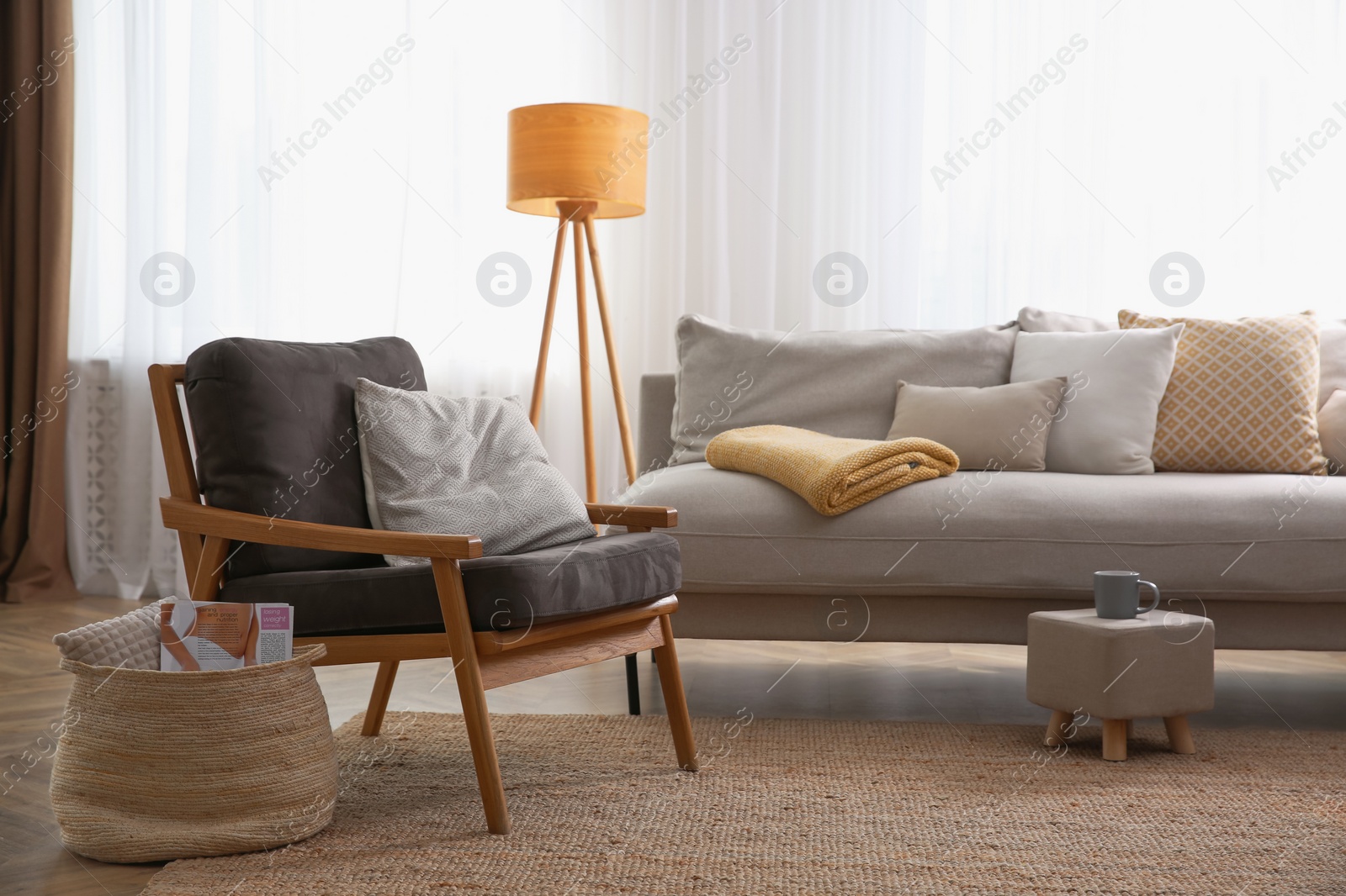 Photo of Comfortable armchair and sofa near window in living room. Interior design