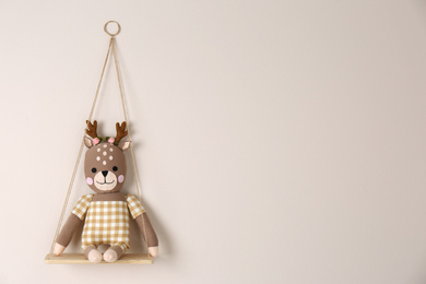 Photo of Shelf with cute toy deer on beige wall, space for text. Child's room interior element
