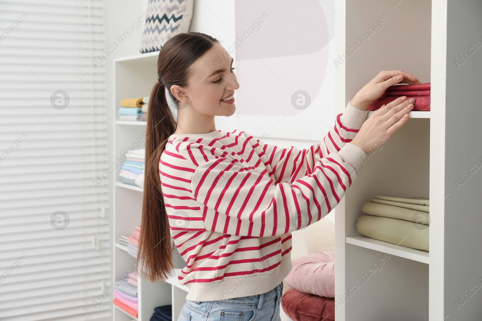 Photo of Smiling young woman choosing bed linens in shop