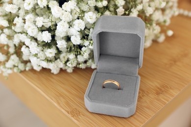 Photo of Box with engagement ring and beautiful bouquet on wooden table. Wedding day