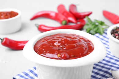 Photo of Bowl of hot chili sauce on table, closeup