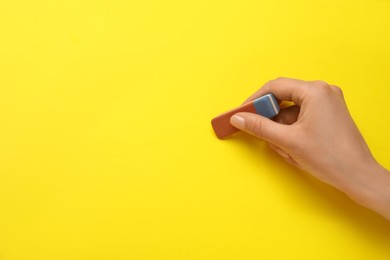 Photo of Woman erasing something on yellow background, closeup. Space for text