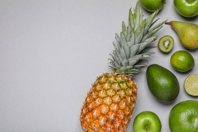 Many different fresh fruits on light grey table, flat lay. Space for text