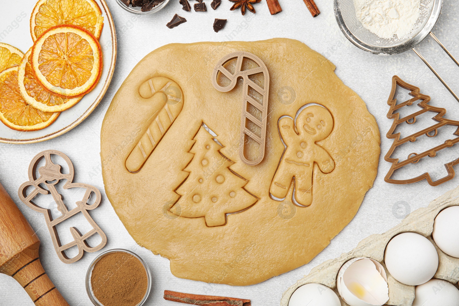Photo of Christmas treat. Flat lay composition with cookie cutters and dough on light table