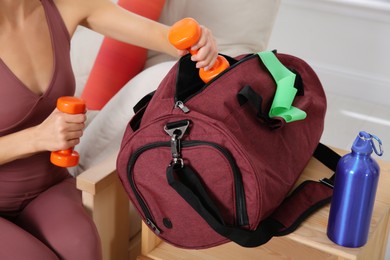 Woman packing sports stuff for training into bag at home, closeup