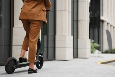 Photo of Businesswoman with modern electric kick scooter on city street, closeup. Space for text