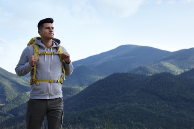 Tourist with backpack in mountains, space for text