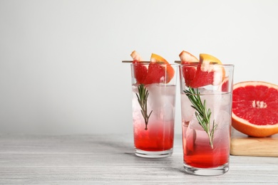 Photo of Glasses of cocktail and grapefruit half on table. Space for text