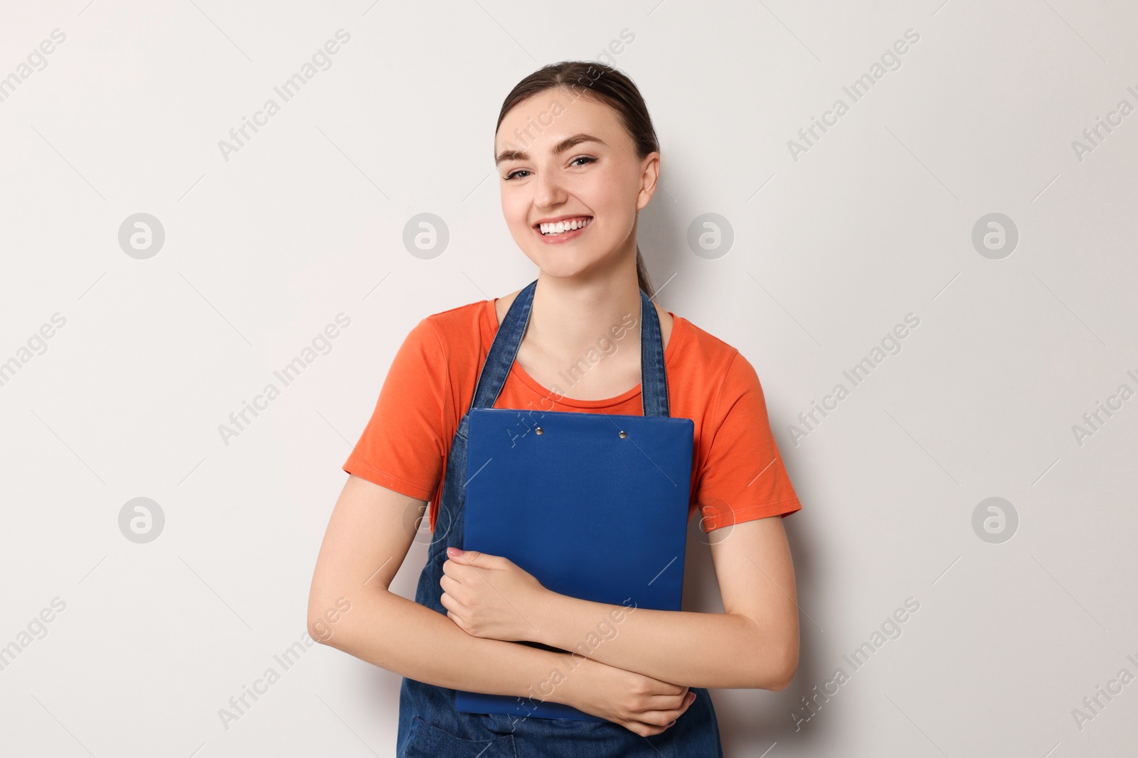 Photo of Beautiful young woman in clean denim apron on light grey background