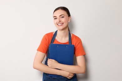 Beautiful young woman in clean denim apron on light grey background