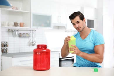 Young athletic man preparing protein shake in kitchen, space for text