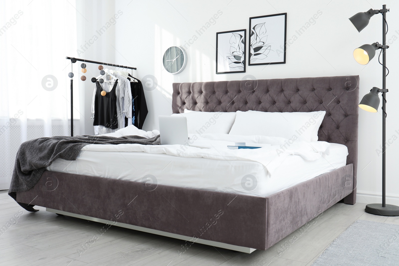 Photo of Stylish room interior with laptop and books on bed