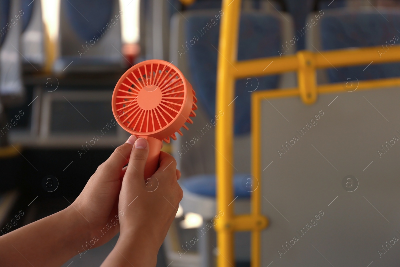 Photo of Woman with portable fan in bus, closeup. Summer heat