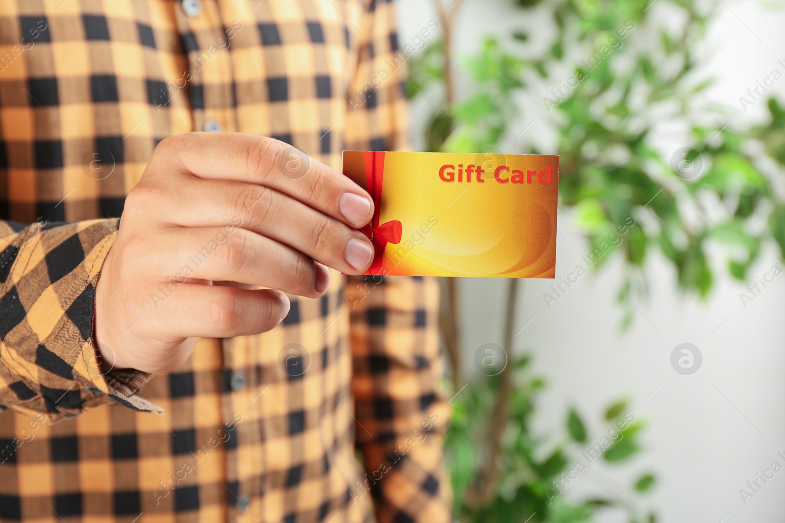 Photo of Man with gift card on blurred background, closeup