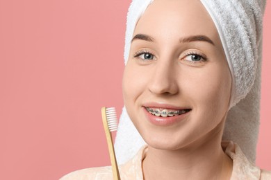 Portrait of smiling woman with dental braces and toothbrush on pink background, closeup. Space for text