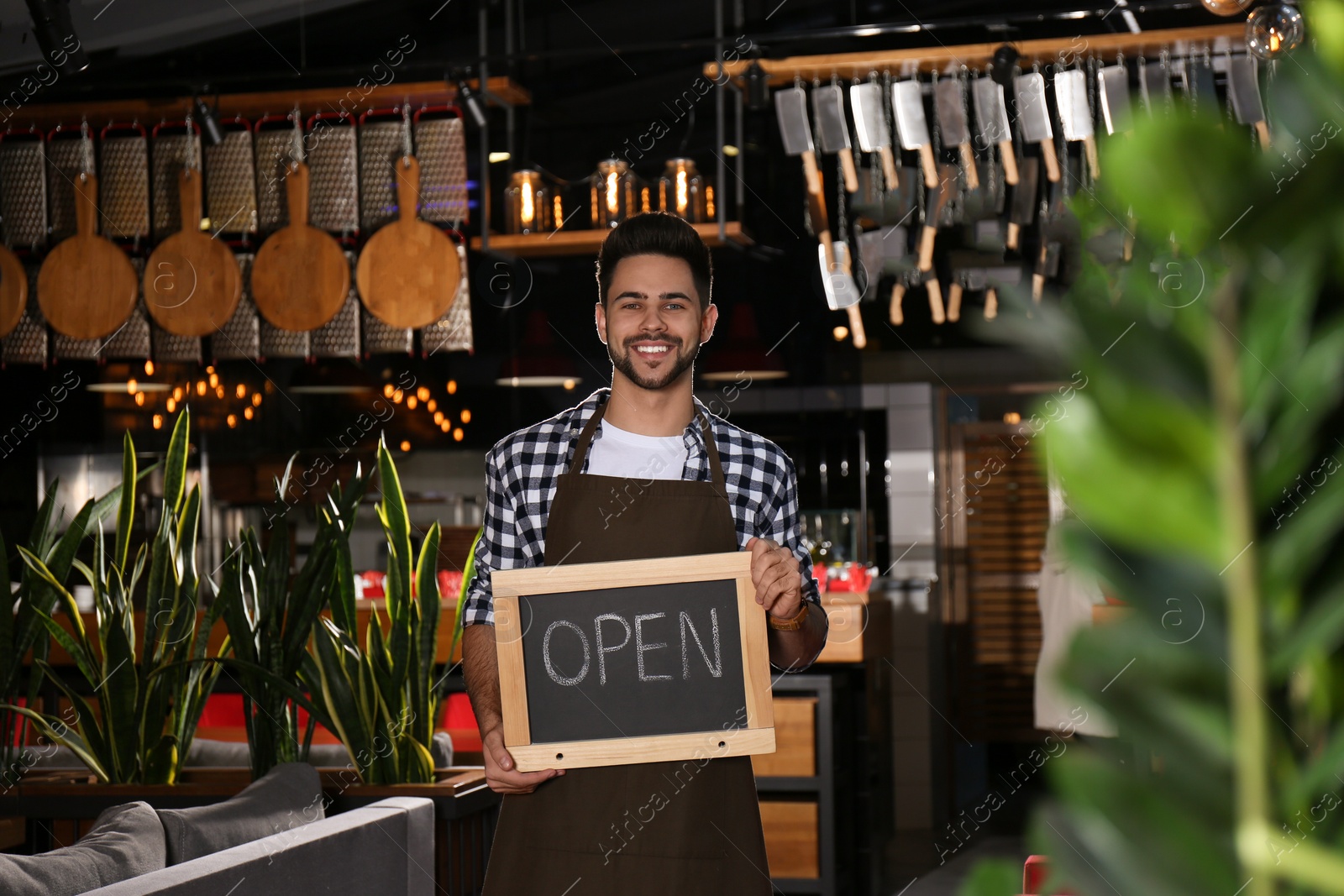 Photo of Young business owner holding sign OPEN in his cafe