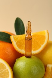 Skincare ampoule with vitamin C, different citrus fruits and leaves on beige background, closeup