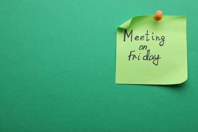 Photo of Paper note with words Meeting on Friday pinned to green background, space for text