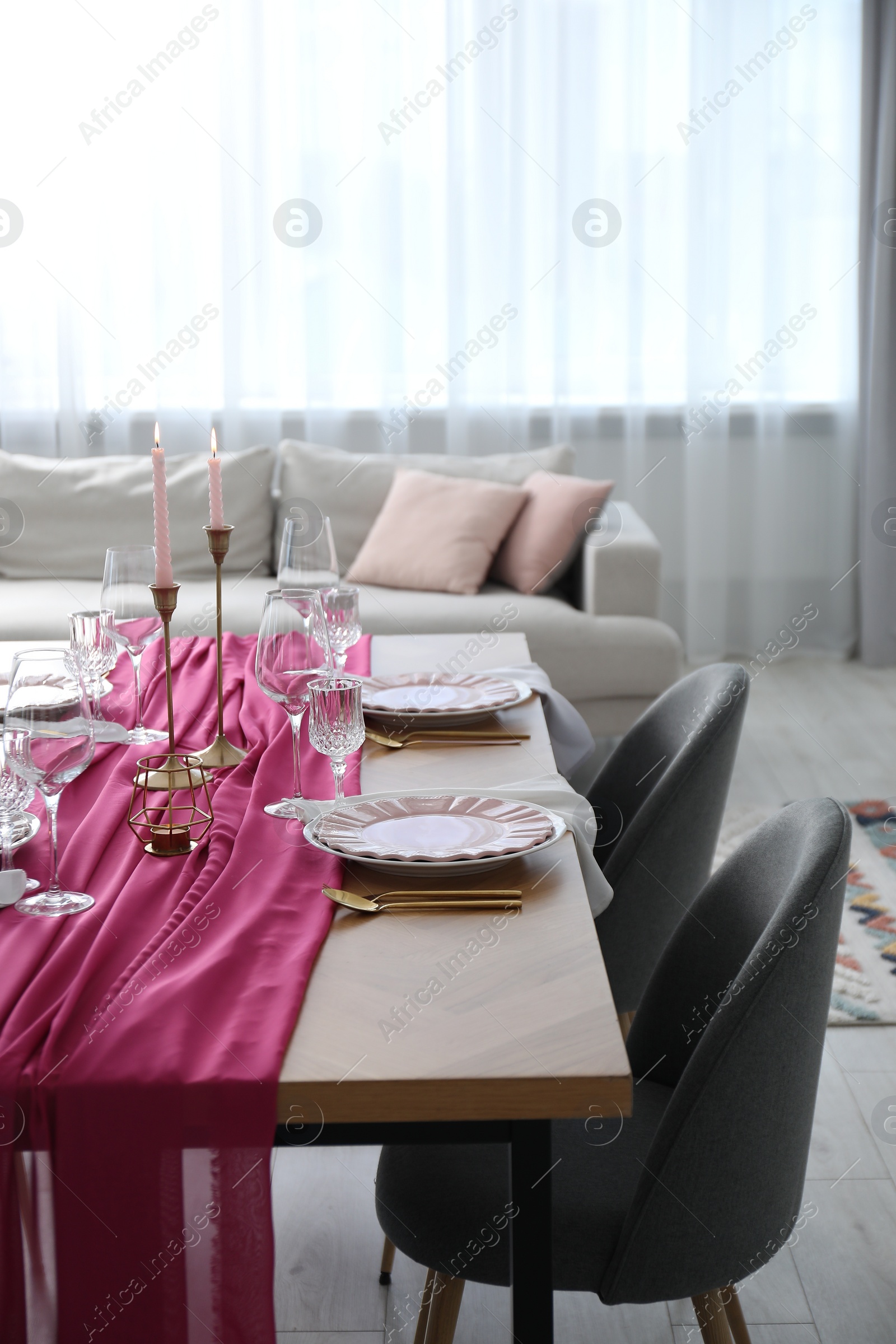 Photo of Beautiful table setting with burning candles and pink accent in dining room