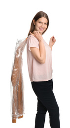 Photo of Young woman holding hanger with dress in plastic bag on white background. Dry-cleaning service