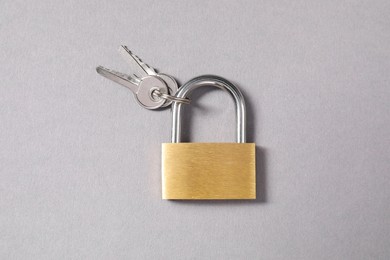 Steel padlock with keys on grey background, top view