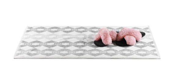 New bath mat with fluffy slippers isolated on white