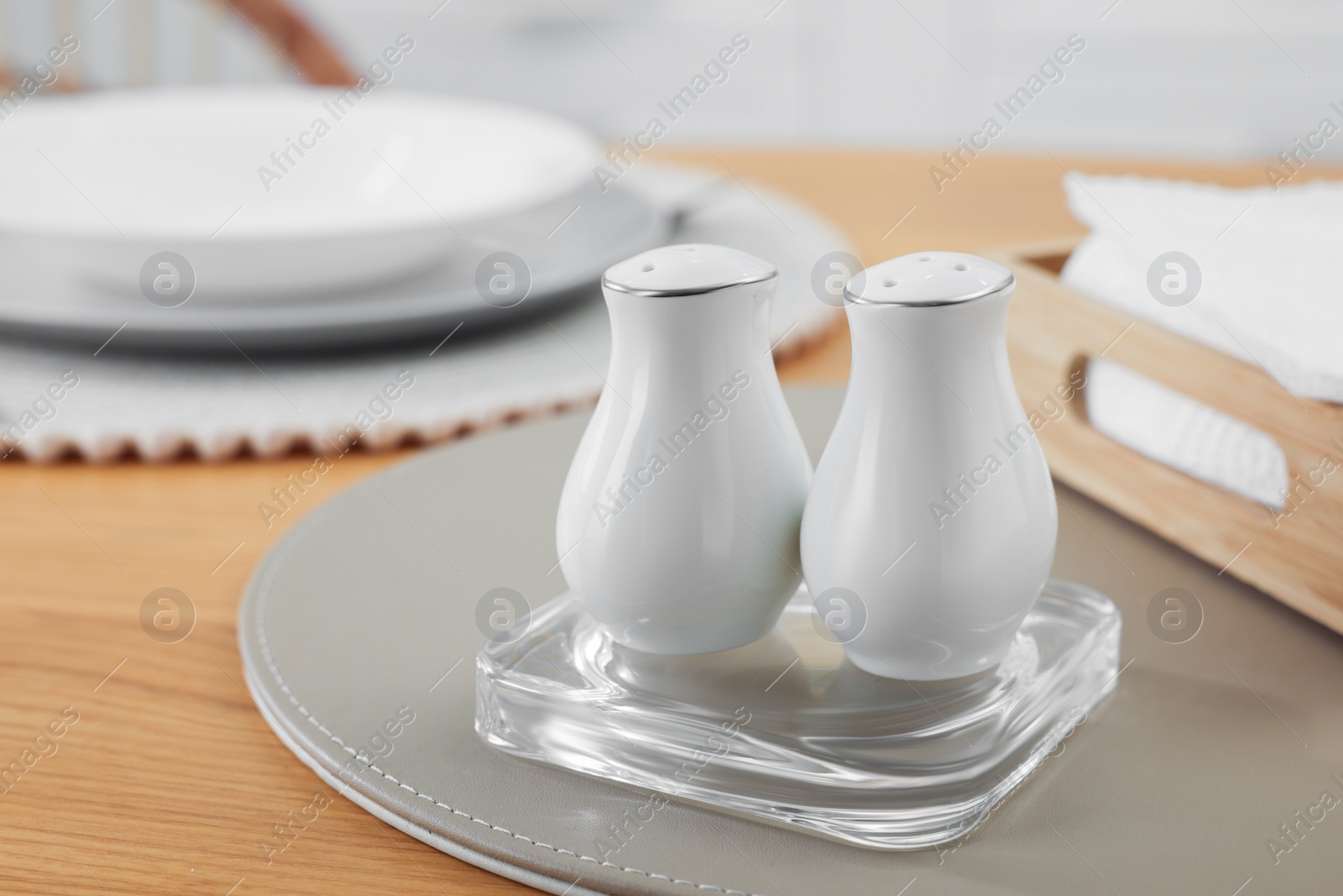 Photo of White ceramic salt and pepper shakers on wooden table, space for text