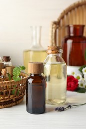 Photo of Aromatherapy. Different essential oils and green leaves on white wooden table