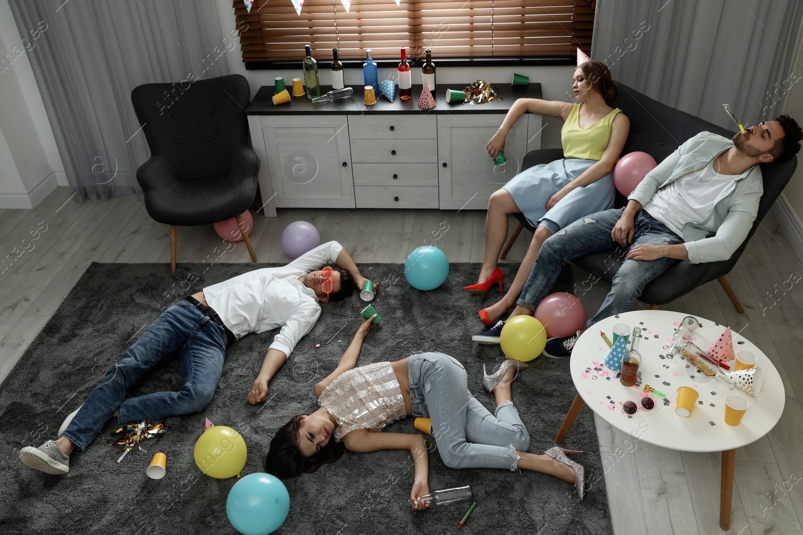 Photo of Group of friends sleeping in messy room after party, view from above