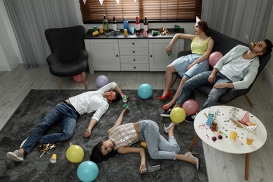 Photo of Group of friends sleeping in messy room after party, view from above