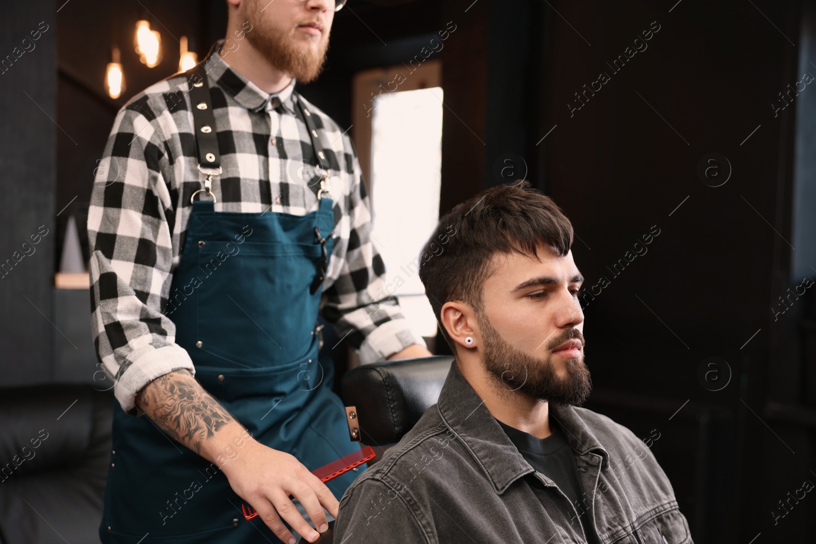 Photo of Professional hairdresser working with bearded client in barbershop