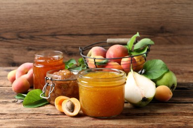 Photo of Jars with different jams and fresh fruits on wooden table