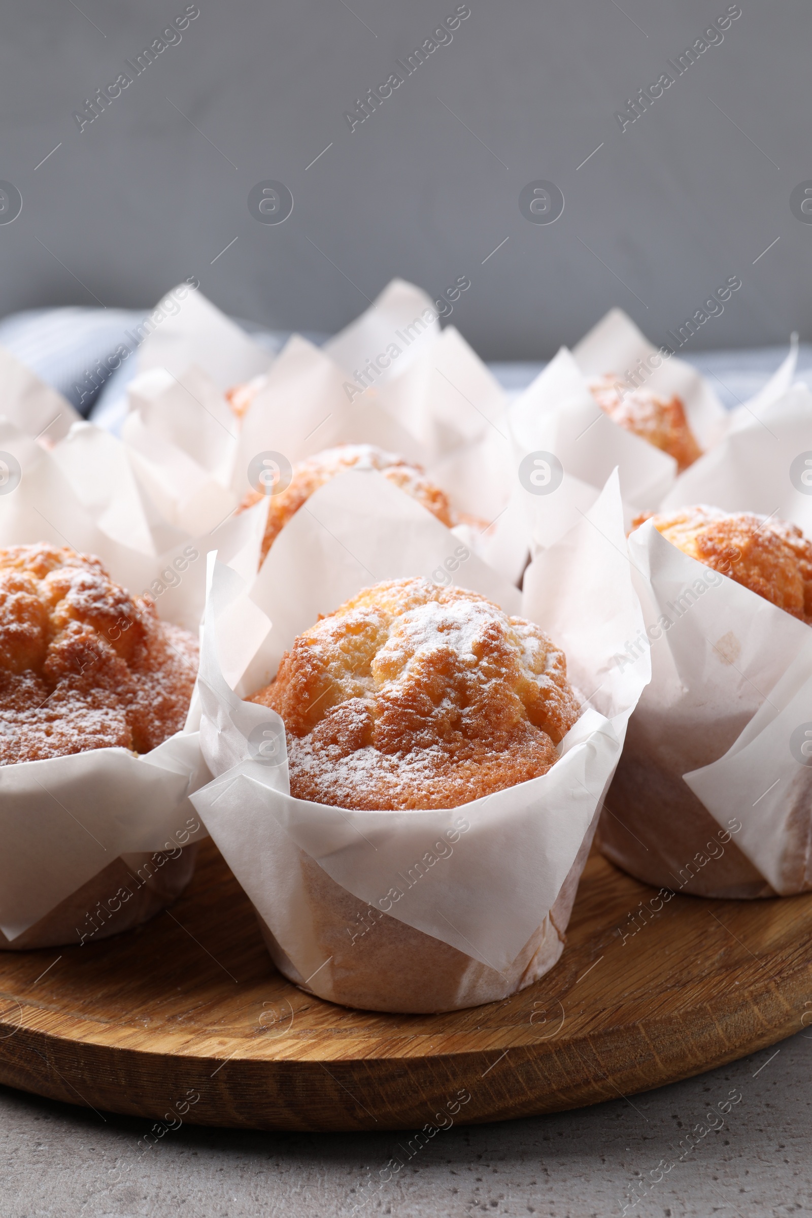 Photo of Delicious muffins with powdered sugar on grey table, closeup