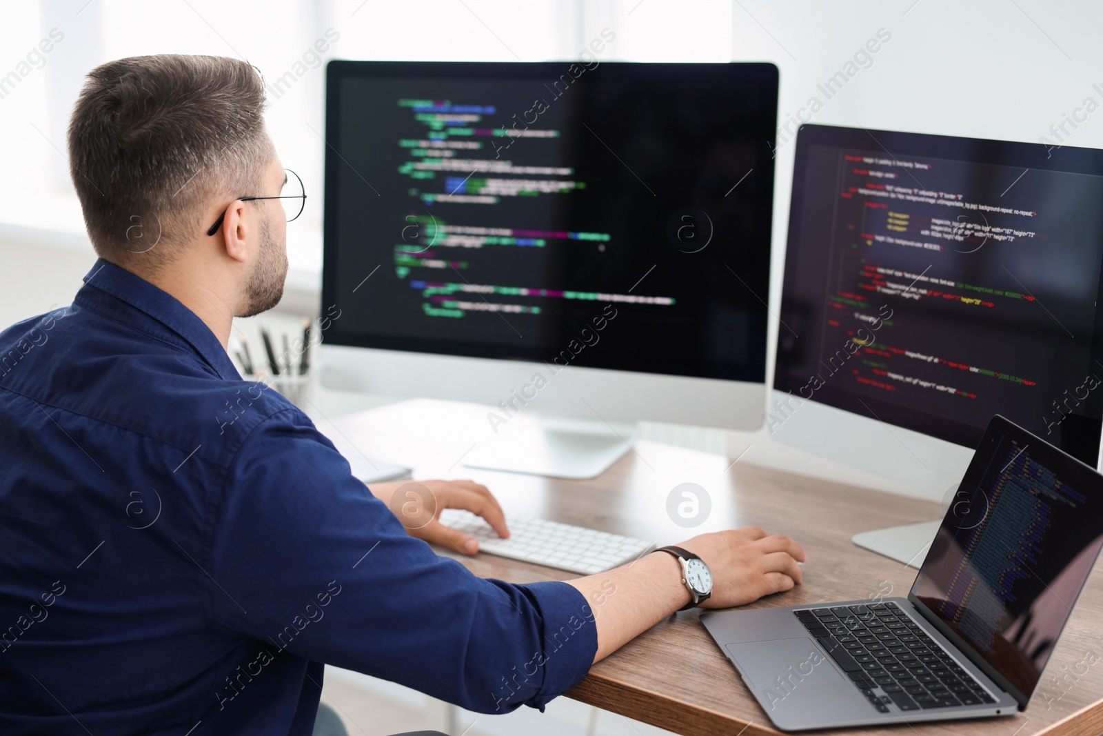 Photo of Young programmer working at desk in office, back view